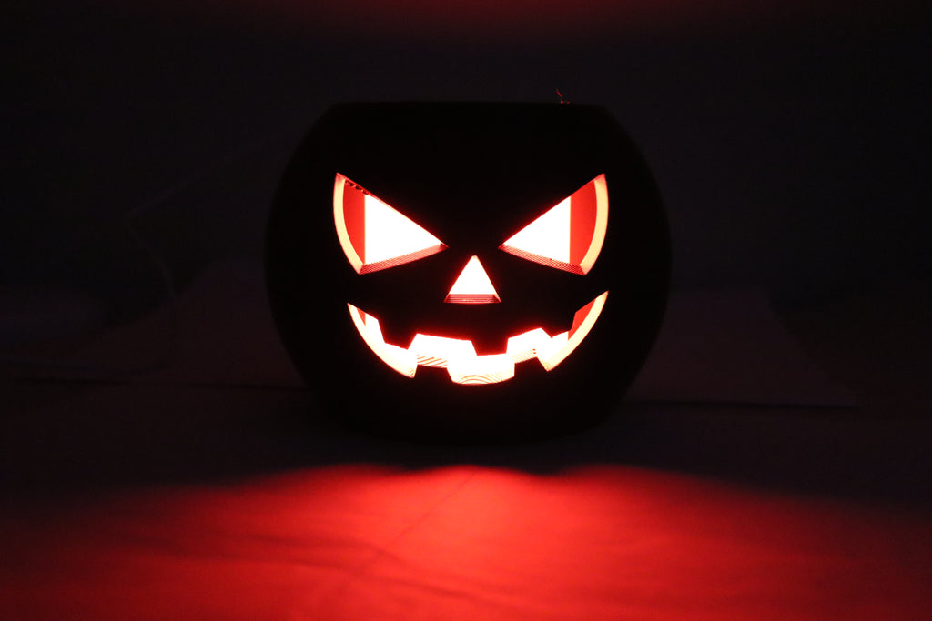 Carved Halloween pumpkin with glowing face on a dark background