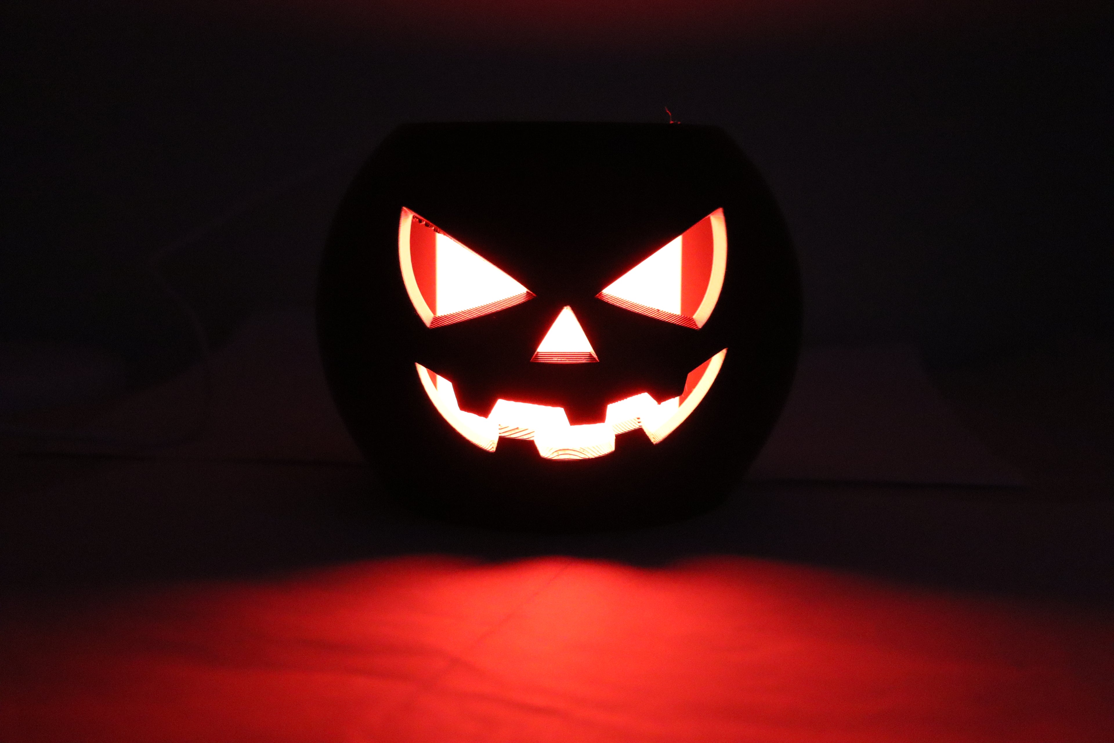 Carved Halloween pumpkin with glowing face on a dark background